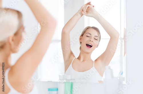 woman yawning in front of mirror at bathroom