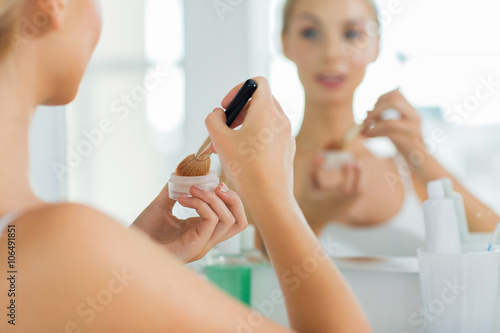 woman with makeup brush and powder at bathroom