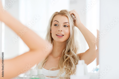happy young woman looking to mirror at bathroom