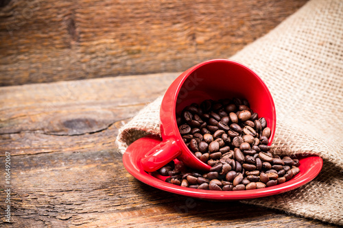 Red coffeecup and plate with spilled coffeebeans photo