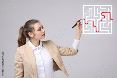 Young woman finding the maze solution  writing on whiteboard.