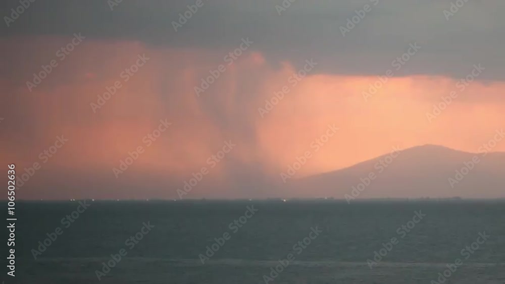 Timelapse shot of thunderstorm. Rain pouring from heavy clouds and lightnings striking over the coastal city and sea Timelapse shot of thunderstorm. Rain pouring from heavy clouds and lightnings striking over the coastal city and sea