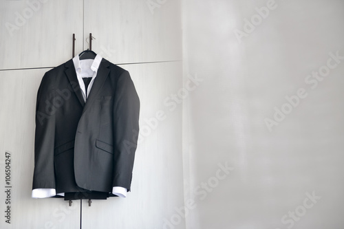 Black suit hanged to a wood closet in natural light