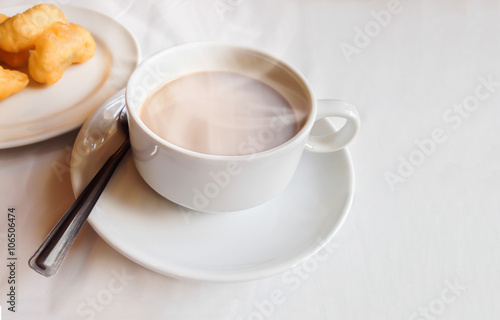 White cup of hot black coffee on white table