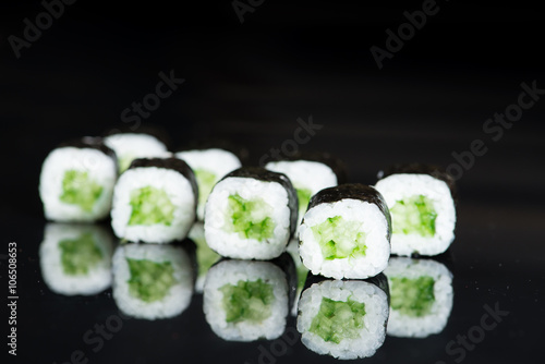 Sushi Roll with cucumber over  black background with reflection