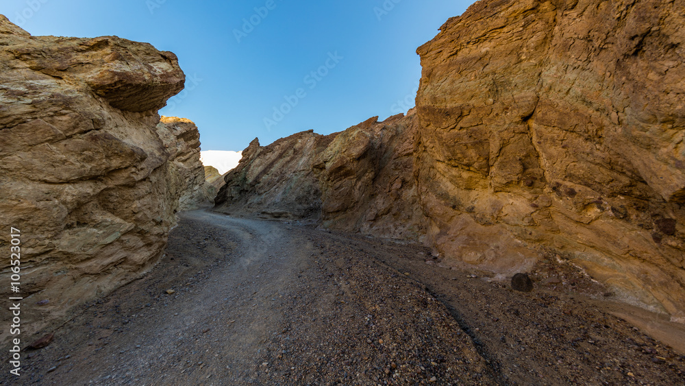 Narrow canyon with vertical walls on both sides. Rocky landscape background. Sandstone formations in Golden canyon, Death Valley