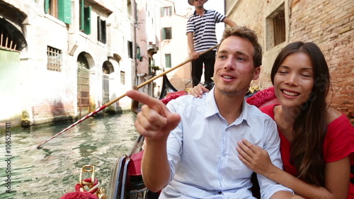 Romantic travel couple in Venice on Gondola ride romance in boat talking happy together on travel vacation holidays. Young multiracial couple sailing in venetian canal in gondole. Italy, Europe