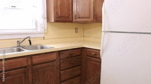a medium wide shot of an out dated old yellow kitchen. Camera moves left and right
