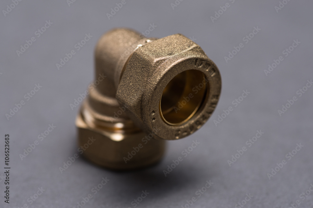 Brass plumbing compression fittings on grey table Brass plumbing compression fittings on grey table