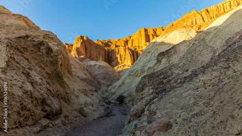 Narrow canyon with vertical walls on both sides. Rocky landscape background. Sandstone formations in Golden canyon, Death Valley