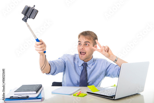  businessman in shirt and tie sitting at office computer desk holding selfie stick shooting self portrait photo photo