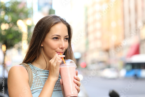Woman eating a milkshake in the street