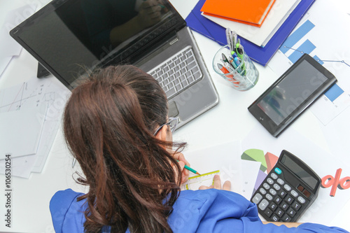 Pretty Business woman analyzing investment charts with calculato photo