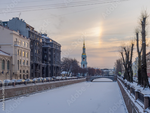 St. Petersburg in the winter. Frozen Canal Griboyedov, the bell tower St. Nicholas Naval Cathedral and the architecture on its banks against the backdrop of a frosty dawn with the sun parhelion
