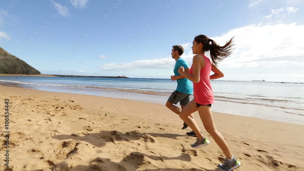 People running on beach training and jogging. Runners couple working out exercising together. Asian woman model and fit Caucasian fitness runner man. People running on beach training and jogging. Runners couple working out exercising together. Asian woman model and fit Caucasian fitness runner man.