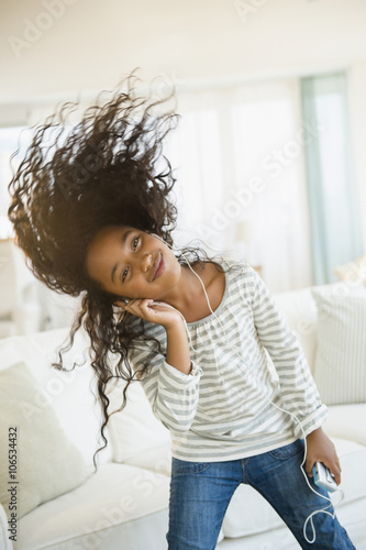 Mixed race girl dancing to headphones in living room