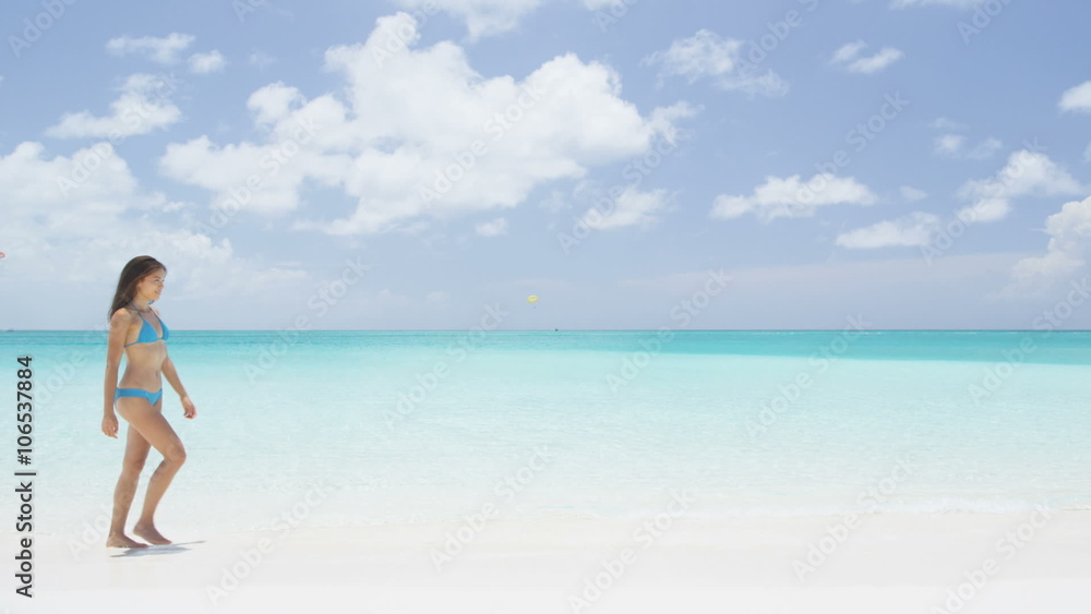 Beach vacation travel woman relaxing in bikini walking on perfect tropical paradise Caribbean beach with turquoise ocean water during summer vacations holidays. Happy lifestyle Asian girl. SLOW MOTION Beach vacation travel woman relaxing in bikini walking on perfect tropical paradise Caribbean beach with turquoise ocean water during summer vacations holidays. Happy lifestyle Asian girl. SLOW MOTION