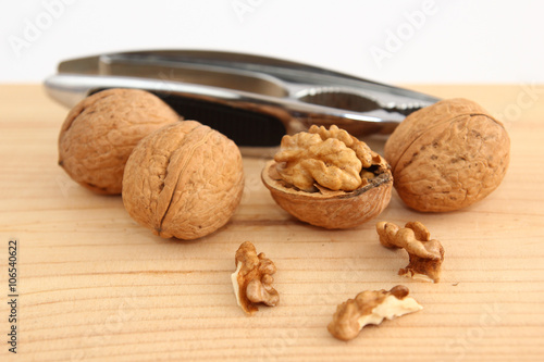 English or Persian walnuts and metal nutcracker on a wooden background.