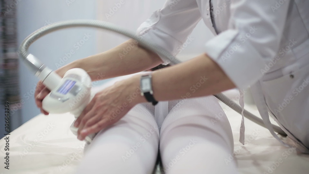 Health and beauty: Girl in specific tights is massaged for reducing cellulite with electronic massage system. Close up Health and beauty: Girl in specific tights is massaged for reducing cellulite with electronic massage system. Close up
