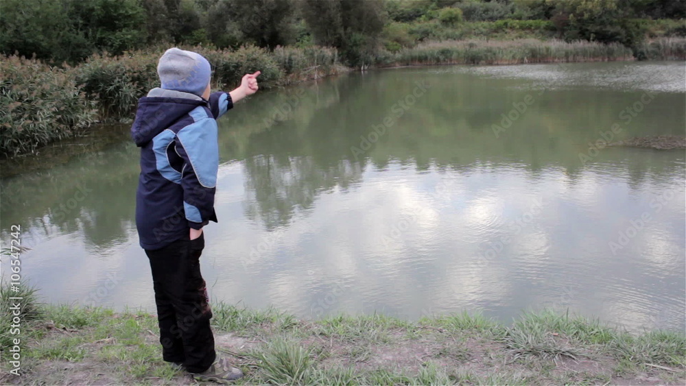 boy on pond/danger boy standing on a cliff coast near the pond and watching boy on pond/danger boy standing on a cliff coast near the pond and watching