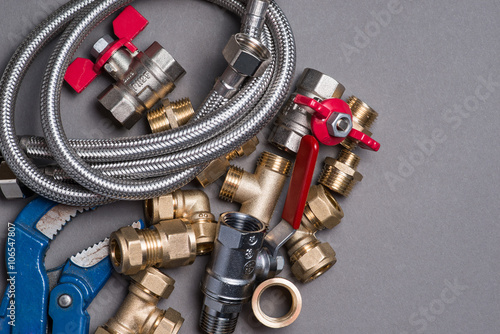 Obraz na plátně Adjustable spanner with assorted plumbing fittings and hose on grey