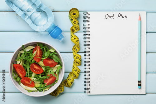 Diet plan, menu or program, tape measure, water and diet food of fresh salad on blue background, weight loss and detox concept, top view