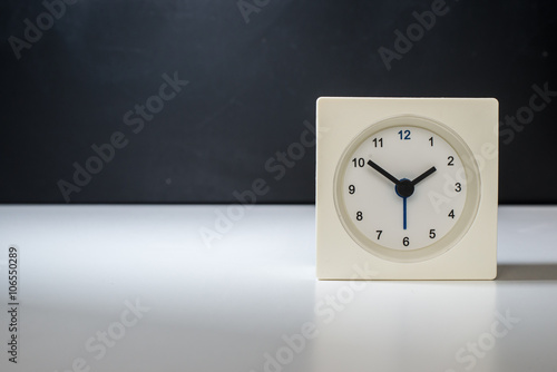 white clock on a white table against the background of black and white board. Black classic glasses