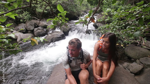 Hiking couple of hikers in outdoor activity wearing backpacks relaxing. Woman and man hiker looking with smiling happy. Healthy lifestyle video from Iao Valley State Park, Wailuku, Maui, Hawaii, USA. photo