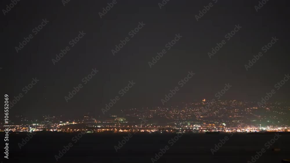 Timelapse shot of getting darker as the night coming. Coastal city is sparkling with bright electric lights and sea water reflecting them Timelapse shot of getting darker as the night coming. Coastal city is sparkling with bright electric lights and sea water reflecting them