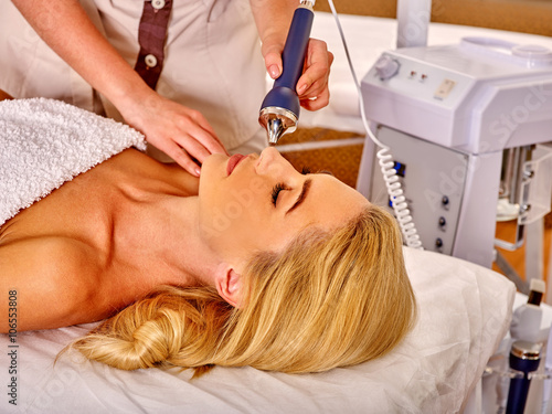 Head of young woman receiving electric ultrusound facial massage at beauty salon. Modern technologies.