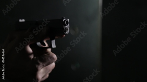 Aiming and shooting a pistol over black background