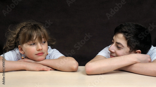 Obraz na plátně Teenagers - a boy and a girl at the table looking at each other