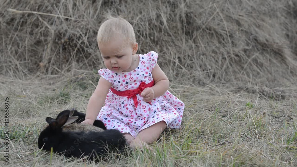 Cute beautiful laughing teen girl on grass with white and black baby rabbit. Selective focus Cute beautiful laughing teen girl on grass with white and black baby rabbit. Selective focus