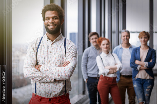 Corporate portrait of young black hipster businessman with his colleagues in background. Post processed with vintage film and sun filter.