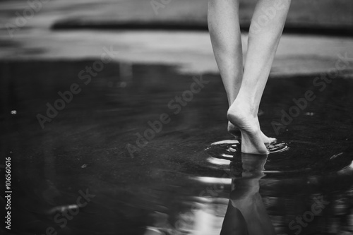 Woman walking barefoot through puddle outdoors