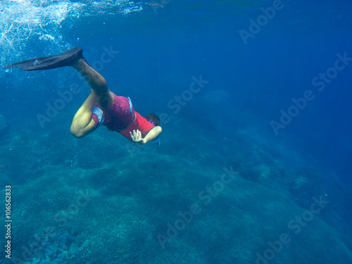 Man in red swimsuit dives to the coral reef © Elya.Q