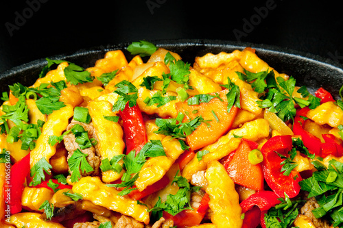 Fried potatoes with meat and vegetables in a pan, junk food
