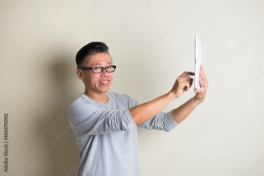 matured asian male using tablet matured asian male using tablet