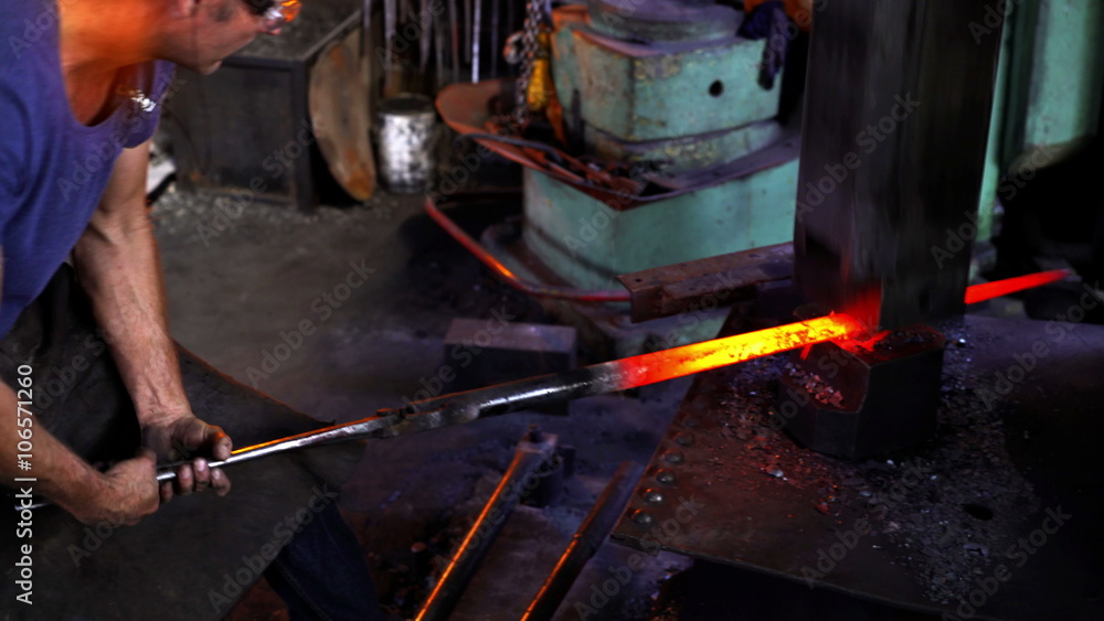 Mechanical hammering of glowing iron in blacksmith forge Mechanical hammering of glowing iron in blacksmith forge