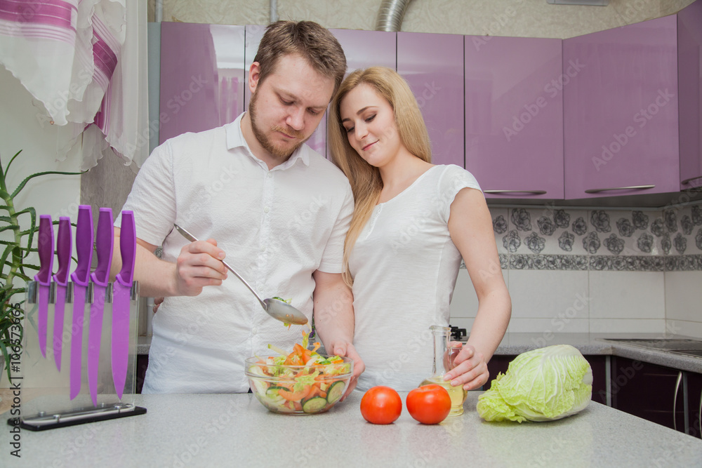 a man and a woman preparing dinner in the kitchen