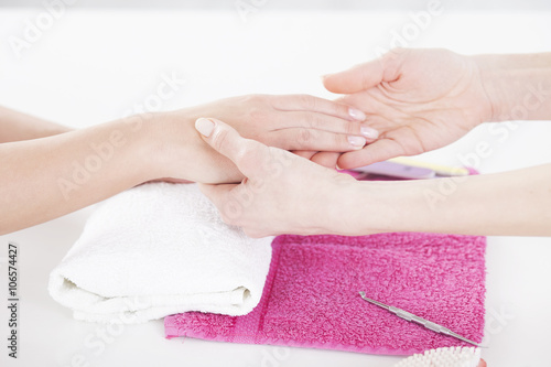 Woman in a nail salon receiving a manicure by a beautician.