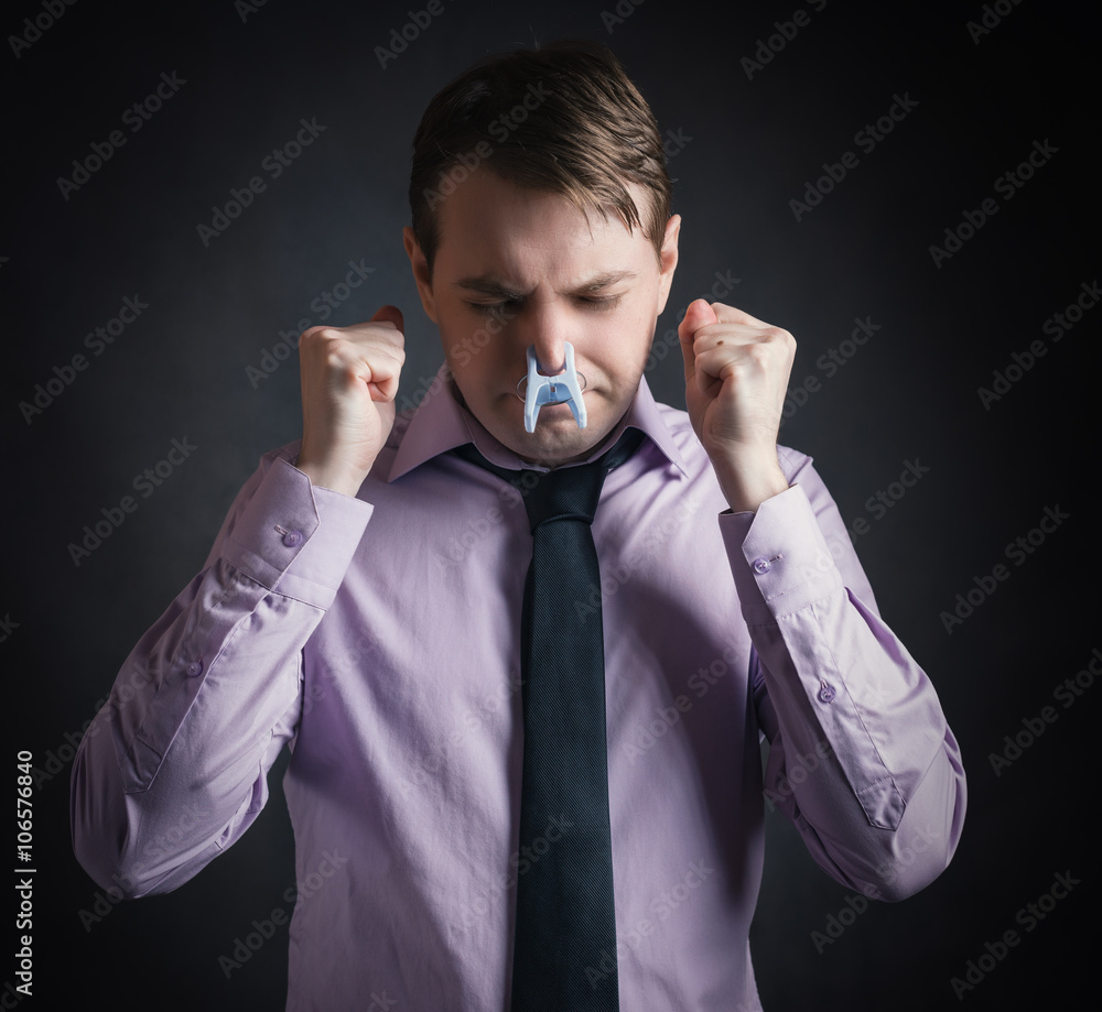 Portrait of young businessman man with clothespin on his nose - bad smell concept photography. Portrait of young businessman man with clothespin on his nose - bad smell concept photography.