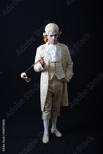 actor in a white suit and wig, holding a theatrical mask