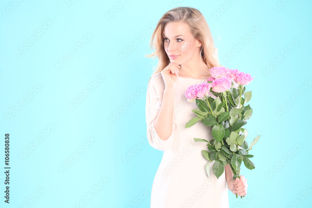 Beautiful woman with a bouquet of roses. Blue background 