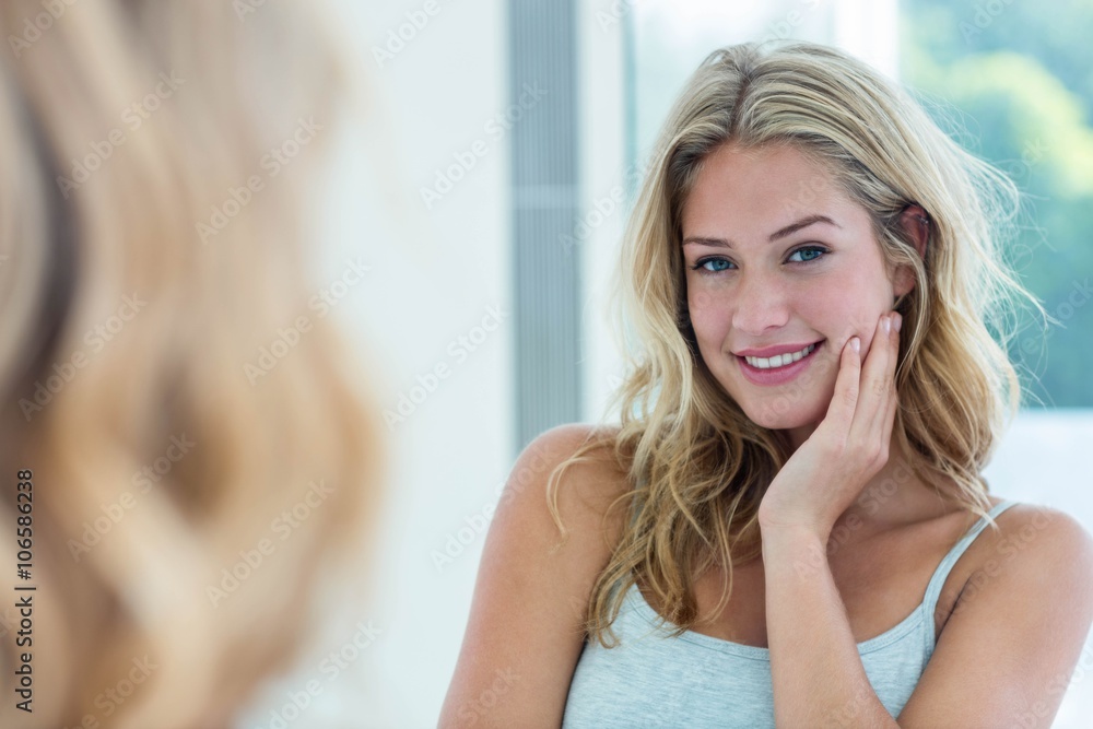 Smiling beautiful young woman looking at herself in the bathroom Smiling beautiful young woman looking at herself in the bathroom
