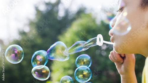 Картината върху платно Close shot of little girl blowing bubbles outside