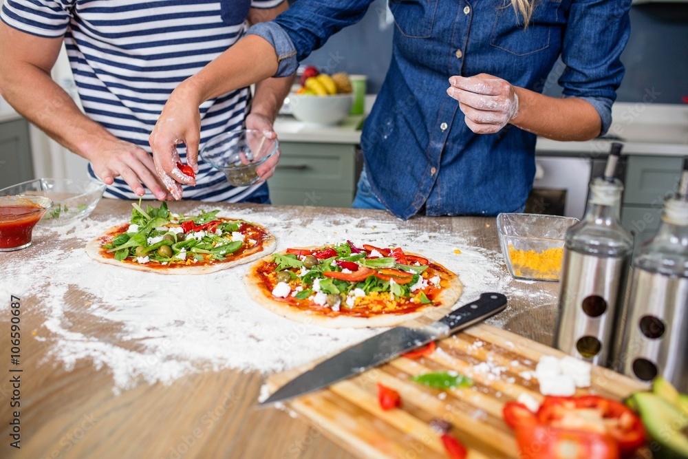 Smiling couple preparing pizza in the kitchen