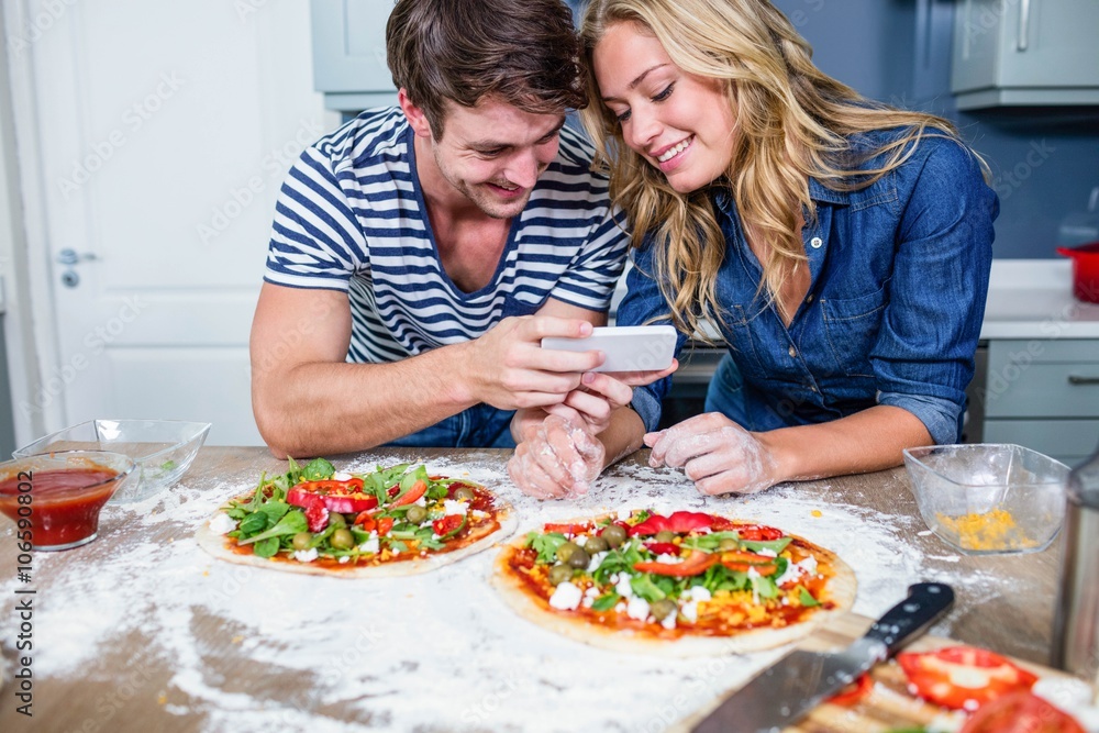 Smiling couple preparing pizza in the kitchen Smiling couple preparing pizza in the kitchen