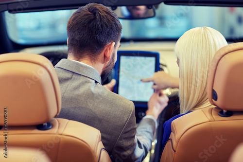 couple sitting in cabriolet car with tablet pc