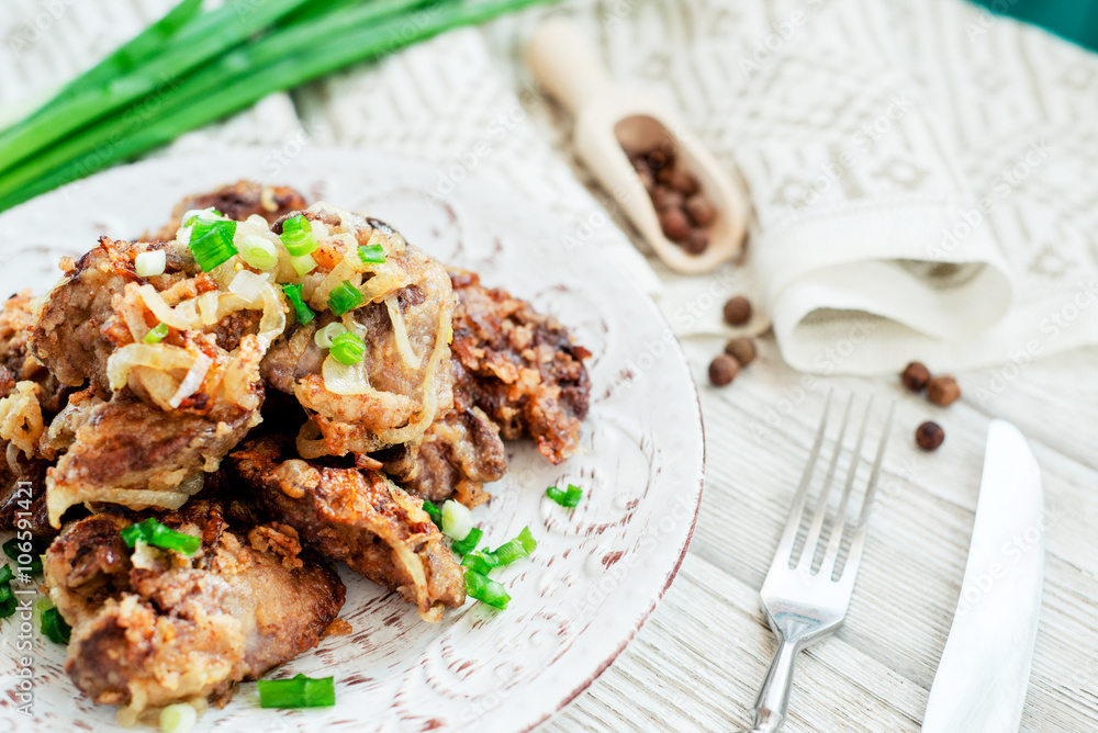 Fried chicken liver with green onion and spices on a wooden background Fried chicken liver with green onion and spices on a wooden background